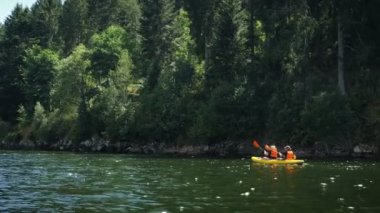 Couple sailing on inflatable boat on lake. People floating on canoe along calm tranquil river. Tourists rowing boat on mountain lake. Woman and man sailing in canoe on scenic lake with mountain view