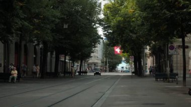 Famous Bahnhofstrasse street in Zurich city, Switzerland, 14.08.22. Morning street of Zurich town in summer with waving national flag. Popular travel destination. Vacation and tourism concept