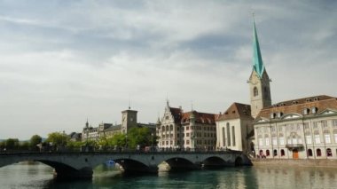 Timelapse of riverbank with bridge and old church tower in old center of Zurich city. Famous tourist old center of Zurich city in Switzerland. Zurich old town center and Limmat river at summertime