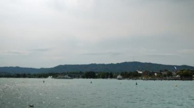 Timelapse of Zurich lake at summer cloudy day. Boats and yachts floating on lake surrounded by green mountains. Tourist ships sailing on lake in Zurich city, Switzerland. Popular travel destination