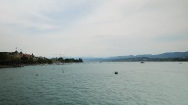 Timelapse of Zurich Lake at weekend. Lot of boats, yachts and catamarans floating on water on lake at summertime. People sailing on tourist ship along beautiful Lake in Zurich. Summer vacation concept