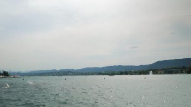 Amazing nature landscape with lake and green mountains on background. Boats and yachts sailing on water on Lake in Zurich. People relaxing on lake, enjoying summertime. Summer vacation concept