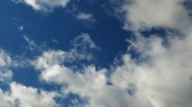 Mavi gökyüzüne karşı kabarık beyaz bulutlar, zaman aşımı. Mavi yaz gökyüzünde bulutlar hızlı hareket ediyor. Bulutlar açık mavi gökyüzünde, güneşli havada uçar. Şaşırtıcı bulut manzarası. Dramatik gökyüzü