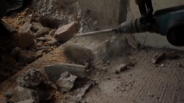 İnşaat alanında çekiç matkapla beton sondajı yapan bir işçi. İnşaatçı yıkım alanında matkap kullanıyor. Tamirat sırasında inşaat işçisi duvarı deliyor. Evlerin iyileştirilmesi ve restorasyonu