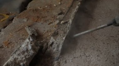 Ev tadilatı. İnşaat işçisi, inşaat alanındaki eski beton duvarı yıkmak için çekiç matkabı kullanıyor. İnşaat konsepti. Matkap yıkım alanında beton kırıyor