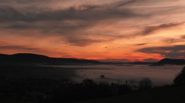 Dağların üzerinde sisli turuncu, mor bir gün doğumu. Gün doğumunda Dağ Vadisi 'nde sabah sisi. Gökyüzüne karşı kara bulutlar ile güzel renkli gün batımı