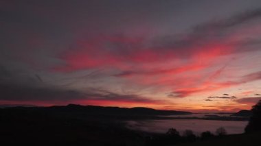 Dağların üzerinde mor pembe günbatımı. Sabah sisi ile renkli, inanılmaz bir gün doğumu. Sonbahar sabahı dağların üzerinde güzel bir gündoğumu. Sabah alacakaranlıkta gökyüzüne doğru hızla hareket eden kara bulutlar.