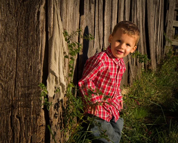 En ung jordbrukare pojke av sin rustika trä lada — 图库照片