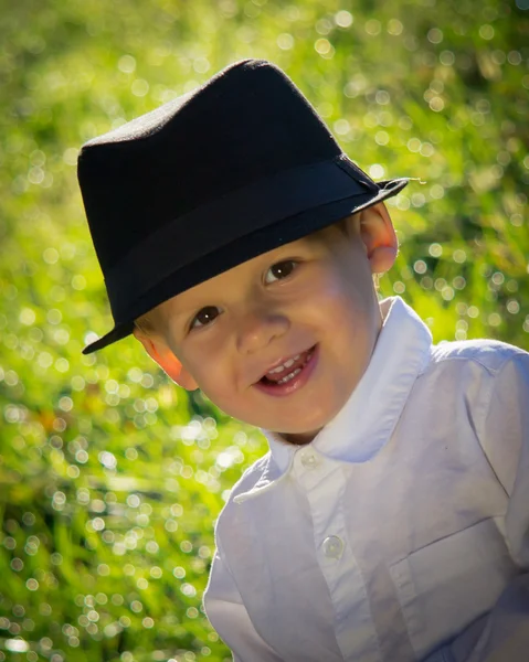 Un jeune garçon avec un sourire charmant et un chapeau noir — Photo