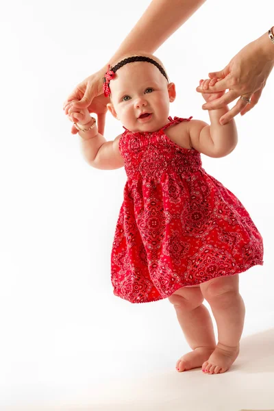 Kleines Mädchen im roten Kleid lernt laufen Stockbild