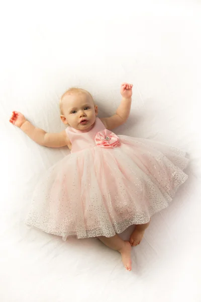 Een meisje van de baby in een roze, frilly jurk — Stockfoto