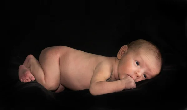 Nu bebê deitado em fundo preto — Fotografia de Stock