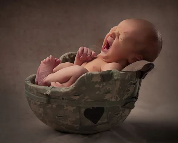 Bébé bâillant dans le casque de l'armée — Photo