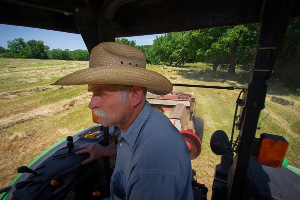 Farmář na traktoru haying pole — Stock fotografie