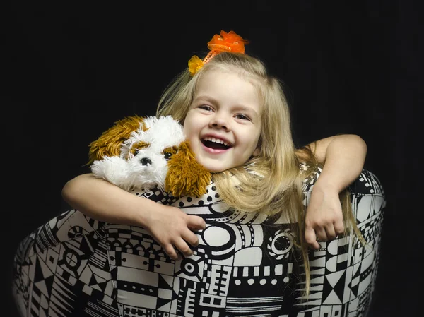 Uma menina com um brinquedo macio na cadeira . — Fotografia de Stock