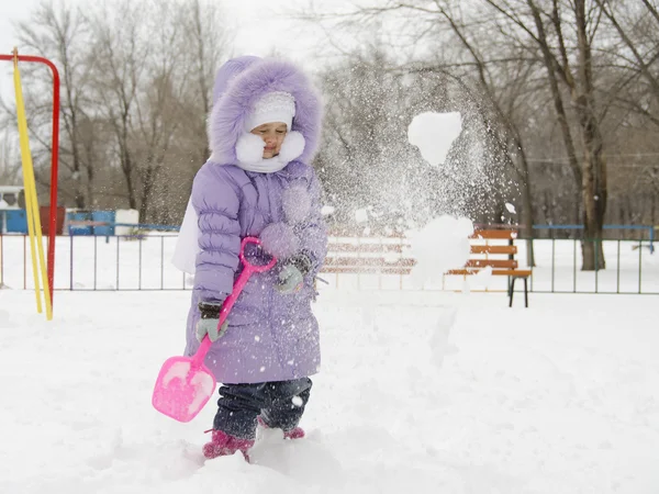 Fyra-åriga flickan kastade sig med snö skyfflar — Stockfoto