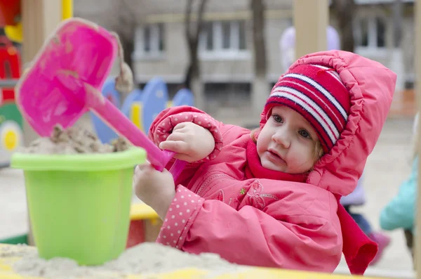 The little girl pours sand in the bucket in the sandbox — Stock Photo, Image