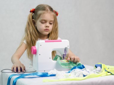Girl sewing on the sewing machine clipart