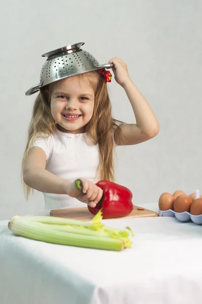 Girl playing in the cook put on a colander on his head — Stock Photo, Image