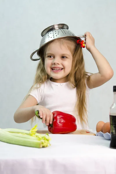 Chica jugando en el cocinero puso en un colador en su cabeza — Foto de Stock