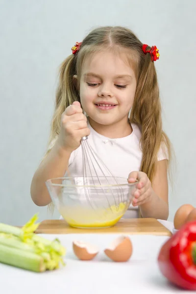 Cook karmaşası içinde oynayan kız bir cam kasede yumurta çırpma — Stok fotoğraf