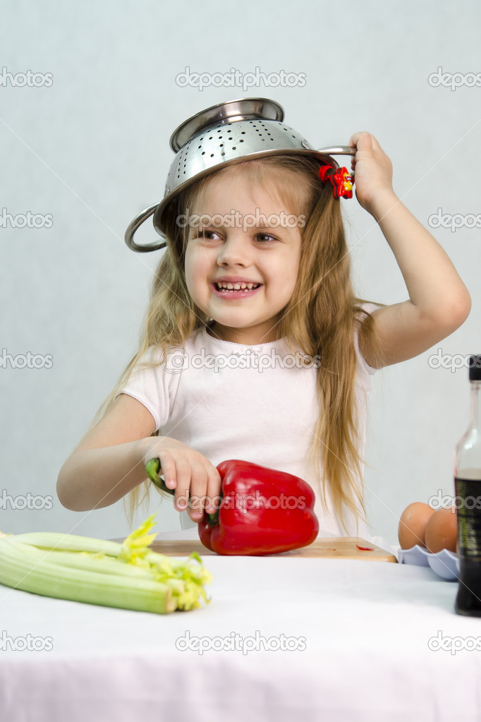 Girl playing in the cook put on a colander on his head