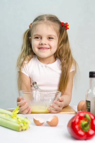 Girl playing in a cook churn whisk the eggs in a glass bowl — Stock Photo, Image