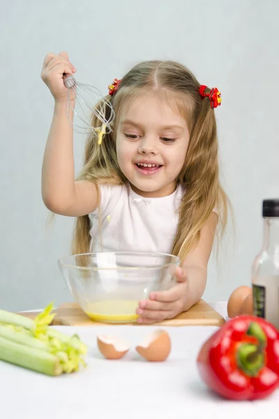 Mädchen, das in einer Kochschüssel spielt, verquirlt die Eier in einer Glasschüssel — Stockfoto
