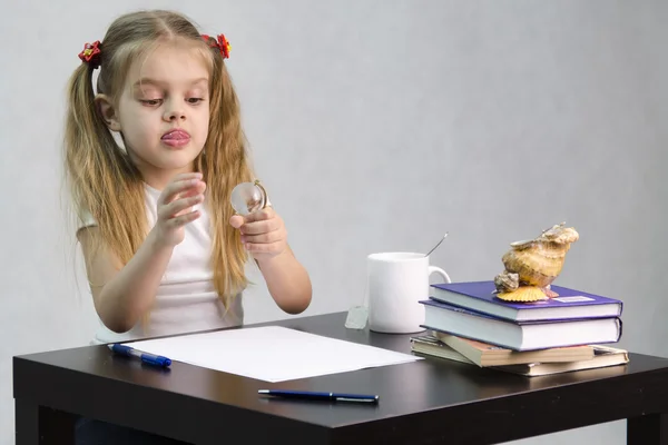 Dívka zamyšleně a bez námahy promění skleněné koule, sedící u stolu v obraze spisovatel — Stock fotografie