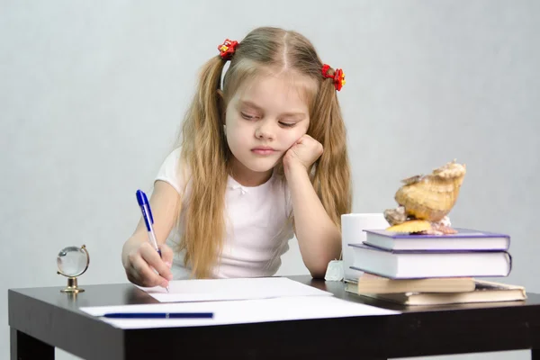 Het meisje schrijft op een stuk papier zitten aan de tafel in het beeld van de schrijver — Stockfoto