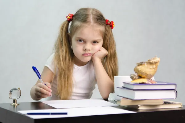 Dívka píše na kousek papíru, sedí u stolu v obrazu spisovatel — Stock fotografie