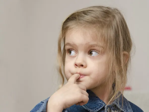 Four-year-old girl with a finger in mouth look left Royalty Free Stock Images