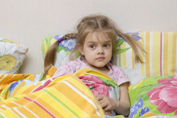 Four-year-old girl with pigtails lying in bed under the blanket — Stock Photo, Image