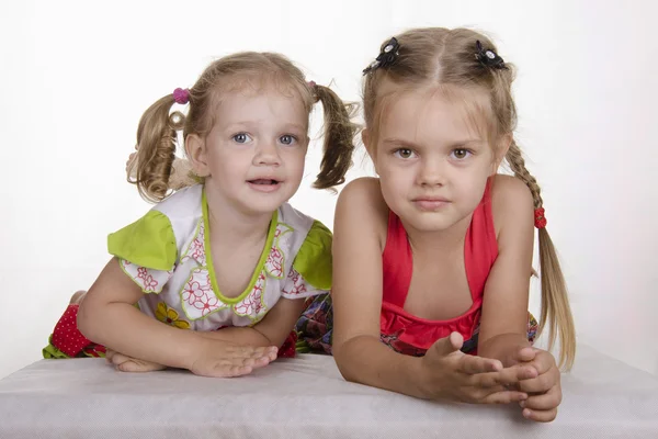 De twee meisjes leggen leunend op zijn handen en kijken in het frame — Stockfoto