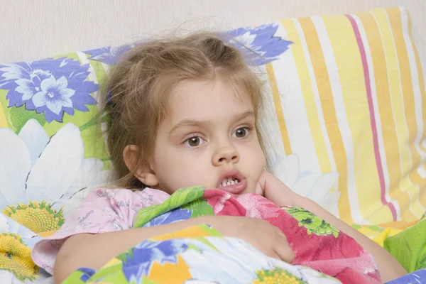 Four-year-old girl is in bed under the blanket Stock Picture