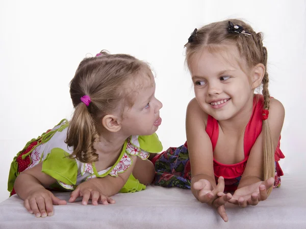 Two girls lie, one tongue, the other smiles — Stock Photo, Image