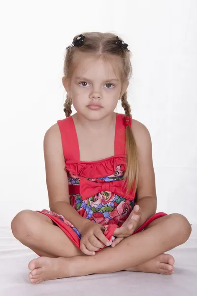 Dziewczyna w sukience siedzi i patrzy się ramki — Zdjęcie stockowe