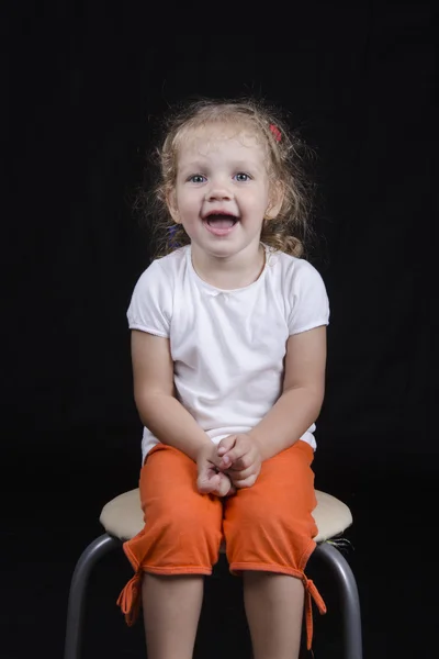 Retrato de uma menina sorridente em um fundo preto — Fotografia de Stock