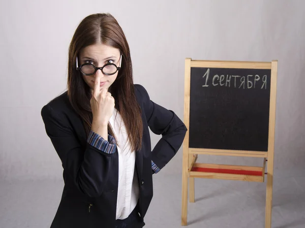 Portrait of the teacher поправляющего spectacles on his nose and Board in the background — Stok fotoğraf