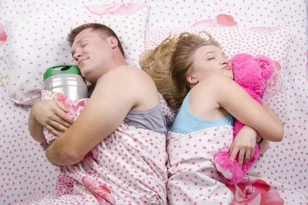 The couple in the bed-husband sleeps with a barrel of beer, a wife with a soft toy — Stock Photo, Image