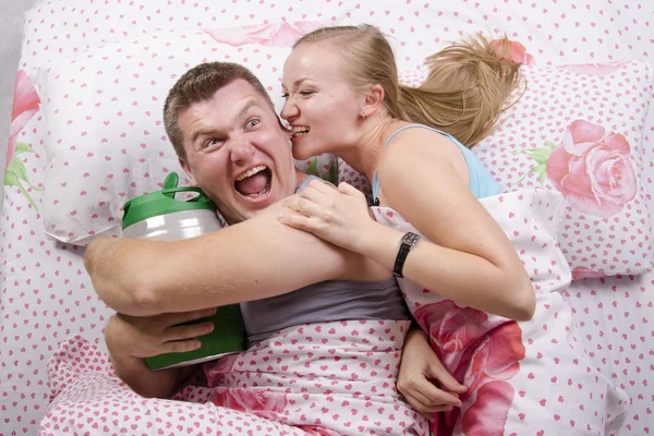 Pareja en la cama: él con un barril de cerveza, ella trata de llevarse —  Fotos de Stock