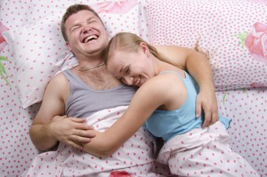 Young couple ежит in bed and laughs