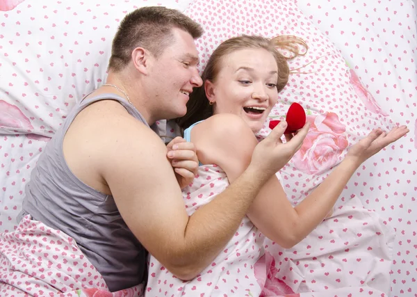 Un giovane uomo dà una ragazza anello sdraiato a letto — Foto Stock