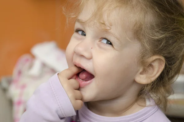 Das kleine Mädchen blickt inbrünstig in einen Schuss und steckt einen Finger in den Mund — Stockfoto