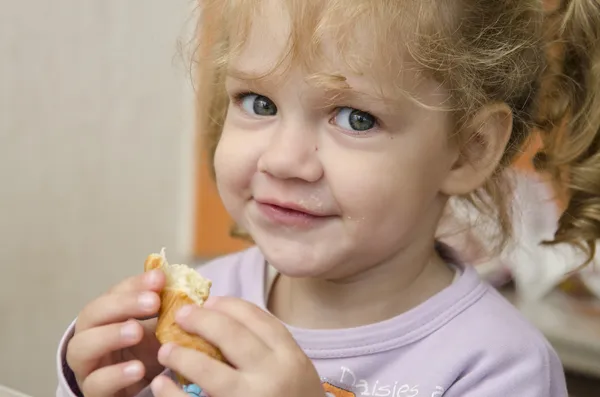 Fetița cu entuziasm și mănâncă o rolă cu plăcere — Fotografie, imagine de stoc