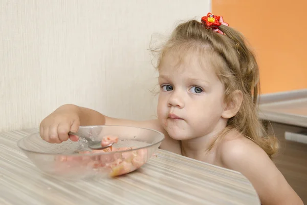 Uma criança com um rosto sombrio come mingau de cereal — Fotografia de Stock