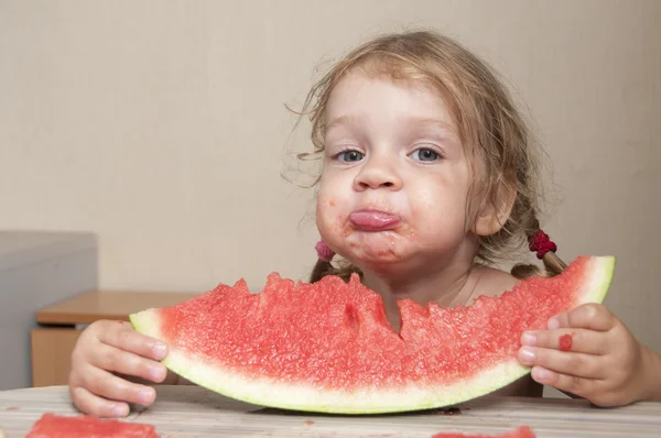 Menina de dois anos comendo melancia com rostos alegres — Fotografia de Stock