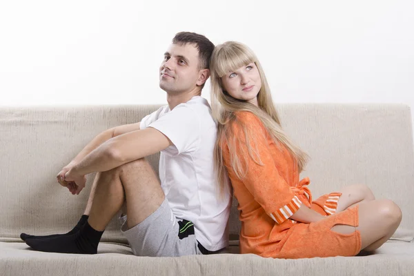 Couple sitting on the couch with his back to each other and looking in the frame — Stock Photo, Image