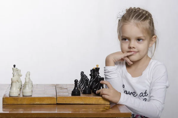 Четырехлетняя девочка с хитрым взглядом, играет в шахматы — стоковое фото