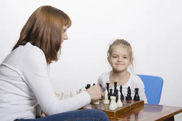 Мать объясняет дочери назначение шахматных фигур — стоковое фото